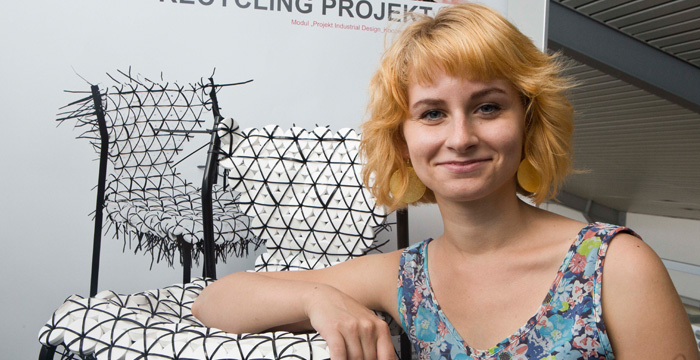 Eine Person lehnt sich mit einem Arm auf eine Stuhlsitzvläche, die aus -mit Kabelbindern verbundenen- Dichtungen besteht.